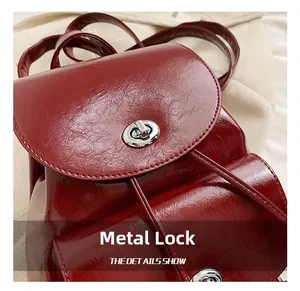 Detalle del cierre giratorio de metal plateado en mochila de cuero rojo borgoña