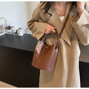 Detailaufnahme der braunen Eimer-Tasche aus strukturiertem Leder mit Seidenschal