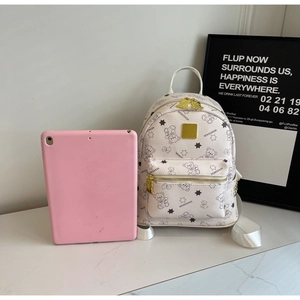 Detailansicht eines weißen Rucksacks aus genarbtem Leder mit Bärenmuster neben einem Tablet