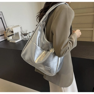 Detail of silver metallic hobo bag with fashion leather tag and textured pleated finish