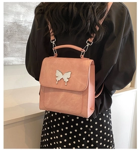 Détail d'un sac à dos rose poudré avec boucle papillon porté par un mannequin
