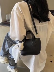 Black lychee leather mini tote bag with adjustable strap and white plush doll pendant