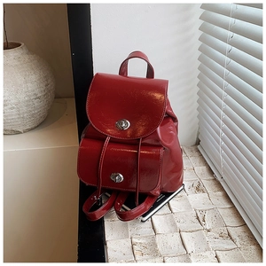 Detalle de mochila de charol rojo brillante con dos cierres giratorios de metal plateado