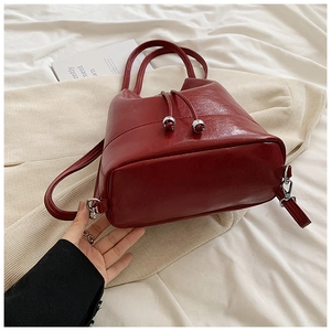 Dettaglio borsa a secchiello bordeaux lucida con coulisse e perline metalliche