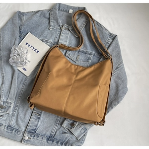 Bruine nylon crossbodytas getoond met een blauw spijkerjack en tijdschrift voor styling