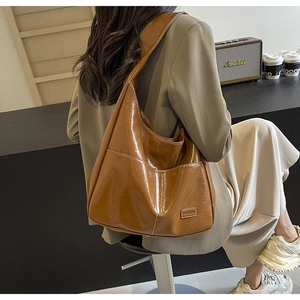 Detailed macro view of the glossy brown oil-wax leather texture on this Hobo tote bag