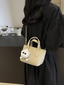Chic beige textured leather mini bucket bag with plush charm and crossbody strap