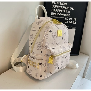 Detailansicht eines weißen Mini-Rucksacks mit Goldnieten und schwarzem Bärenmuster