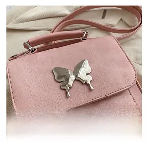 Détail du sac bandoulière rose avec fermoir papillon argenté et texture fine