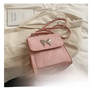 Détail du sac bandoulière rose avec boucle papillon argentée sur tissu beige texturé