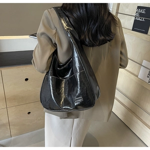 Detail of glossy black pleated tote bag with fine stitching and FASHION label accent