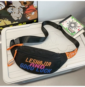 Detailed shot of black nylon chest bag with orange zippers and colorful pixel text