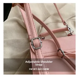 Détail de la bandoulière réglable en cuir rose avec une boucle en métal argenté