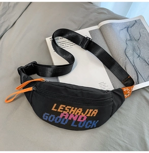 Detail of black nylon waist bag featuring colorful pixelated letters and orange zipper pull