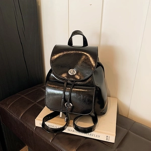 Detalle de mini mochila negra brillante con cierre giratorio de metal y cordón ajustable