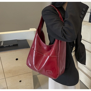 Detailed view of wine red patent leather tote with white stitching and fashion label