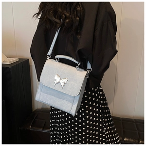 Vue latérale d'un sac bandoulière bleu clair avec fermoir papillon argenté sur un modèle