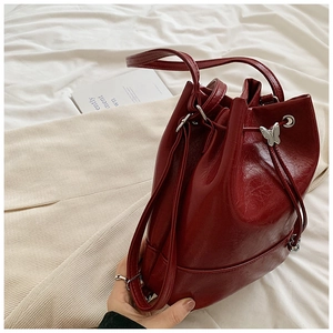 Dettaglio borsa a secchiello rossa vintage in pelle cerata con ciondolo a farfalla