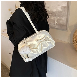Detail of pearl white bowling bag with bows and cloud charm on a black blazer