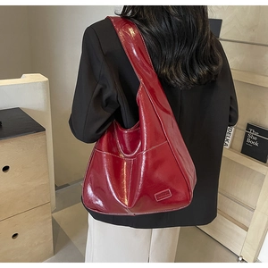 Detailed view of the dark red oiled leather texture and fashion tag on the hobo tote bag