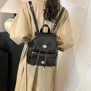 Primer plano de mochila negra brillante con hebilla metálica plateada y cordones fijos