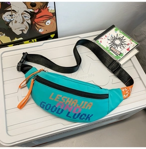 Detail of teal nylon fanny pack with orange zipper pulls and printed lettering