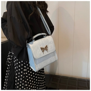 Gros plan du sac bandoulière en cuir bleu clair avec boucle papillon dorée élégante