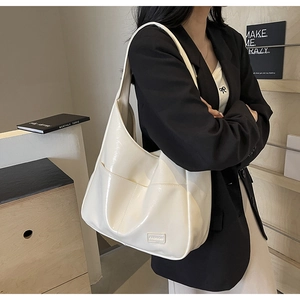 Close-up of beige glossy patent leather tote bag with a small fashion tag detail
