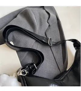 Détail de la bandoulière réglable en cuir noir avec boucle argentée et texture de sac plissé