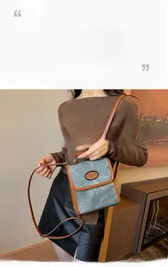 Detail of vintage suede satchel bag featuring denim blue fabric and brown leather flap