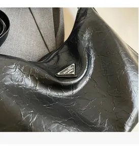 Gros plan sur la texture du cuir plissé brillant et le logo triangulaire en métal argenté