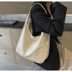 Detail of cream faux leather tote bag showing textured surface and fashion brand plaque
