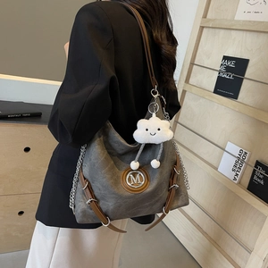 Detail of grey large capacity tote bag with leather strap and cloud charm pendant