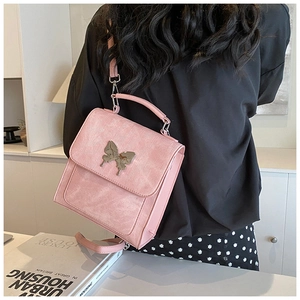 Détail d'un sac à main rose avec fermoir papillon en métal poli et poignée supérieure