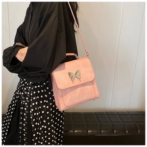 Détail du petit sac bandoulière rose vintage avec ornement papillon en métal argenté
