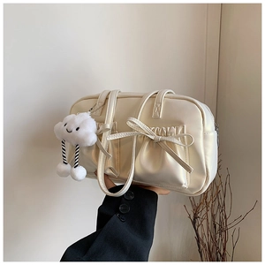 Close-up of cream bowling bag with bow pocket and cute cloud plush keychain detail