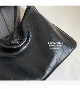 Détail d'un cabas en cuir froissé noir avec logo triangulaire et texture vintage