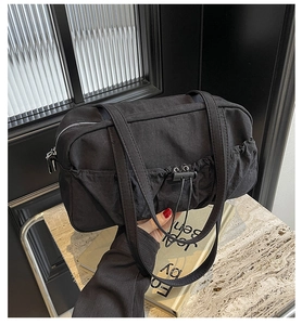 Top-down view of a stylish black pleated tote bag with drawstring side pockets on marble