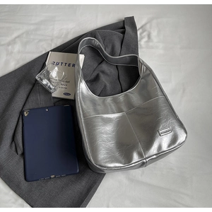 Flat lay view of a metallic silver hobo bag with fashion tag and casual accessories