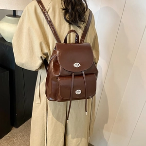 Detalle de mochila vintage marrón brillante con cierres giratorios y cordones ajustables