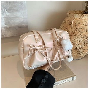 Close-up of pearl pink bowling bag featuring ribbon bow pockets and a plush charm