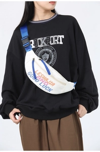 Detail of white canvas waist bag with colorful lettering and adjustable blue strap