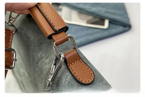 Detail of grey fabric texture with brown leather handle and silver metal hardware