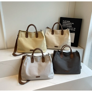 Detail shot of four nylon tote bags in yellow, beige, grey, and charcoal with leather straps