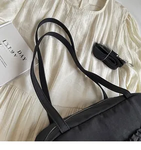 Detail view of smooth adjustable shoulder strap and metal zipper on black tote bag