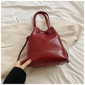 Dettaglio borsa a secchiello in pelle PU lucida rosso intenso con coulisse e occhielli