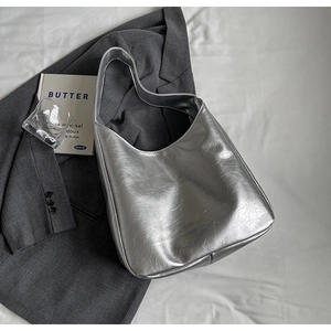 Detail of silver metallic hobo bag with wrinkled leather texture next to a grey blazer