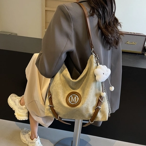 Detail of canvas hobo bag with leather straps and plush cloud pendant accessory