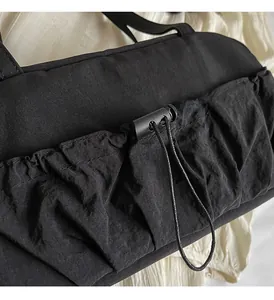 Close-up of black pleated shoulder bag with adjustable drawstring pocket and durable fabric