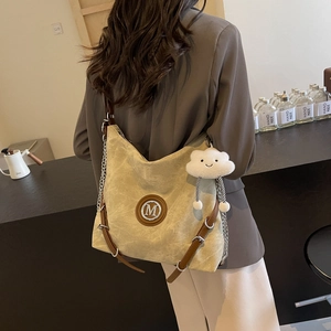 Close-up of khaki canvas backpack with M-logo, leather straps and fluffy cloud charm